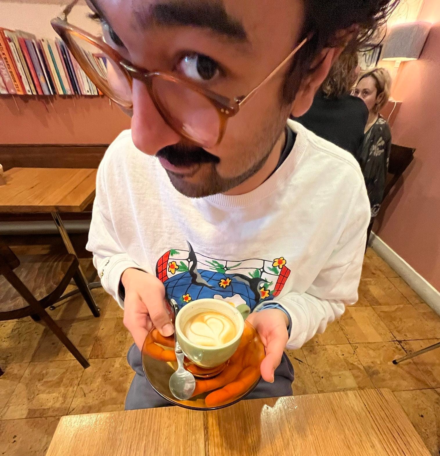 Fish-eye closeup of Andrew holding a cup of coffee looking real keen